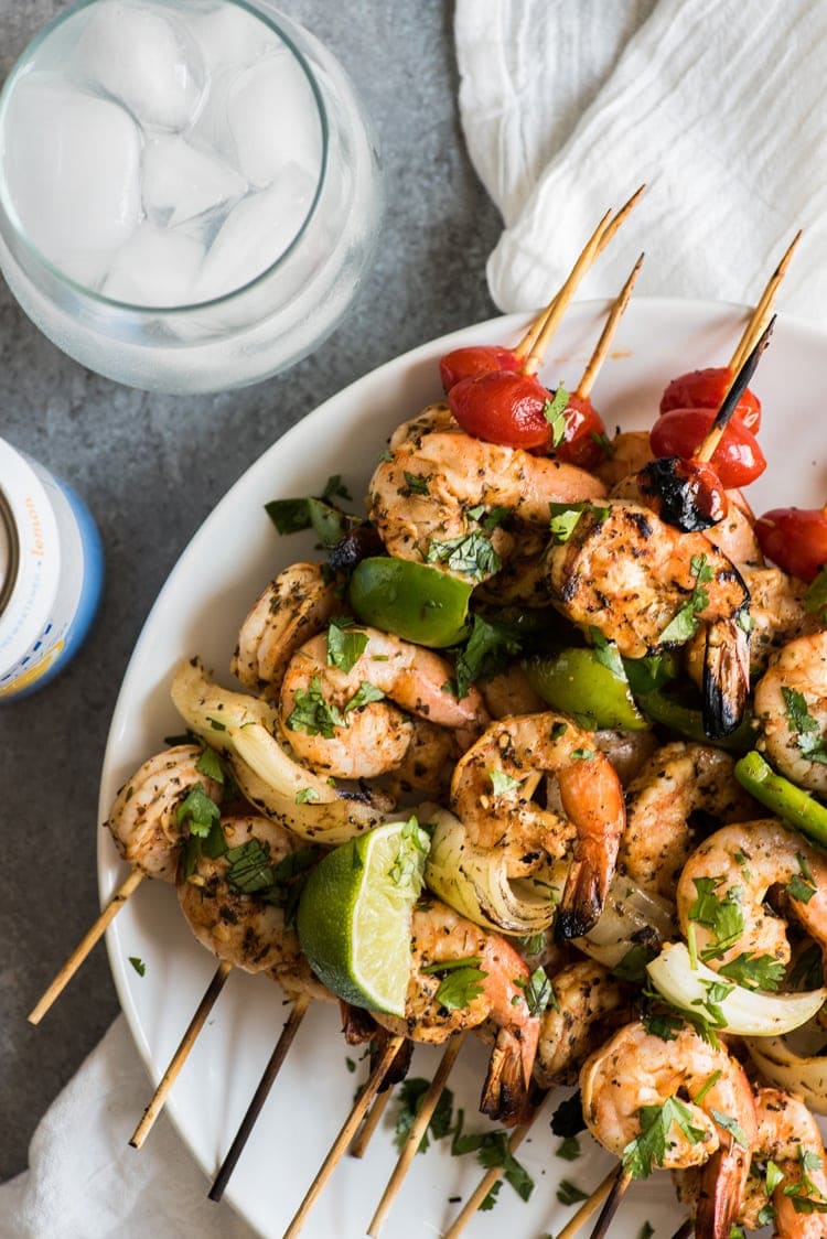 Grilled shrimp skewers topped with cilantro and lime juice.