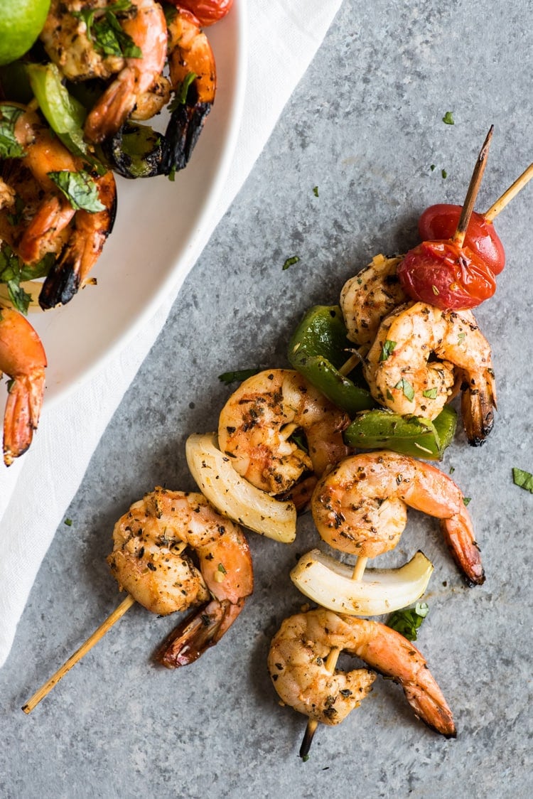 Two skewers of grilled shrimp with tomatoes, onions and bell peppers.