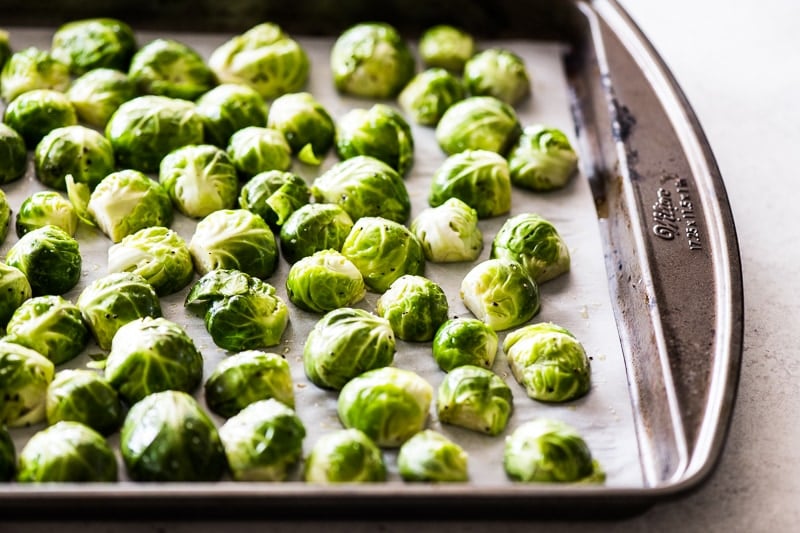 Raw and seasoned brussels sprouts on a pan