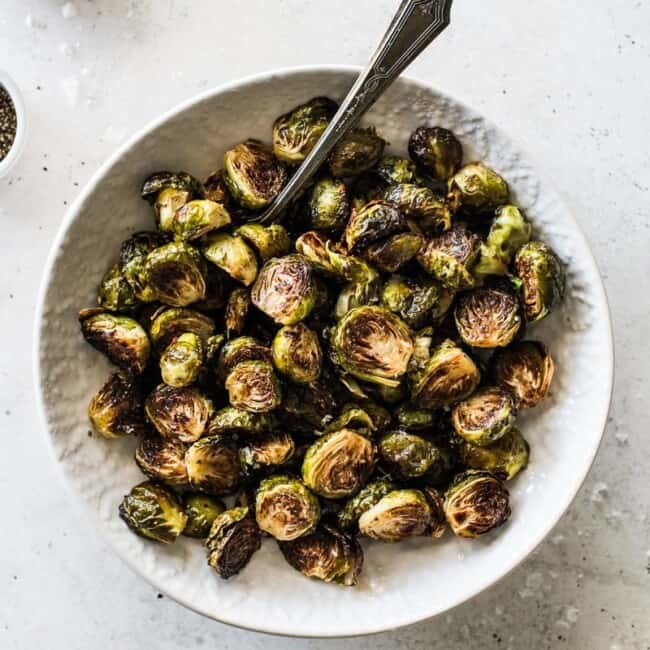 Honey Balsamic Brussel Sprouts in a white bowl topped with sea salt.