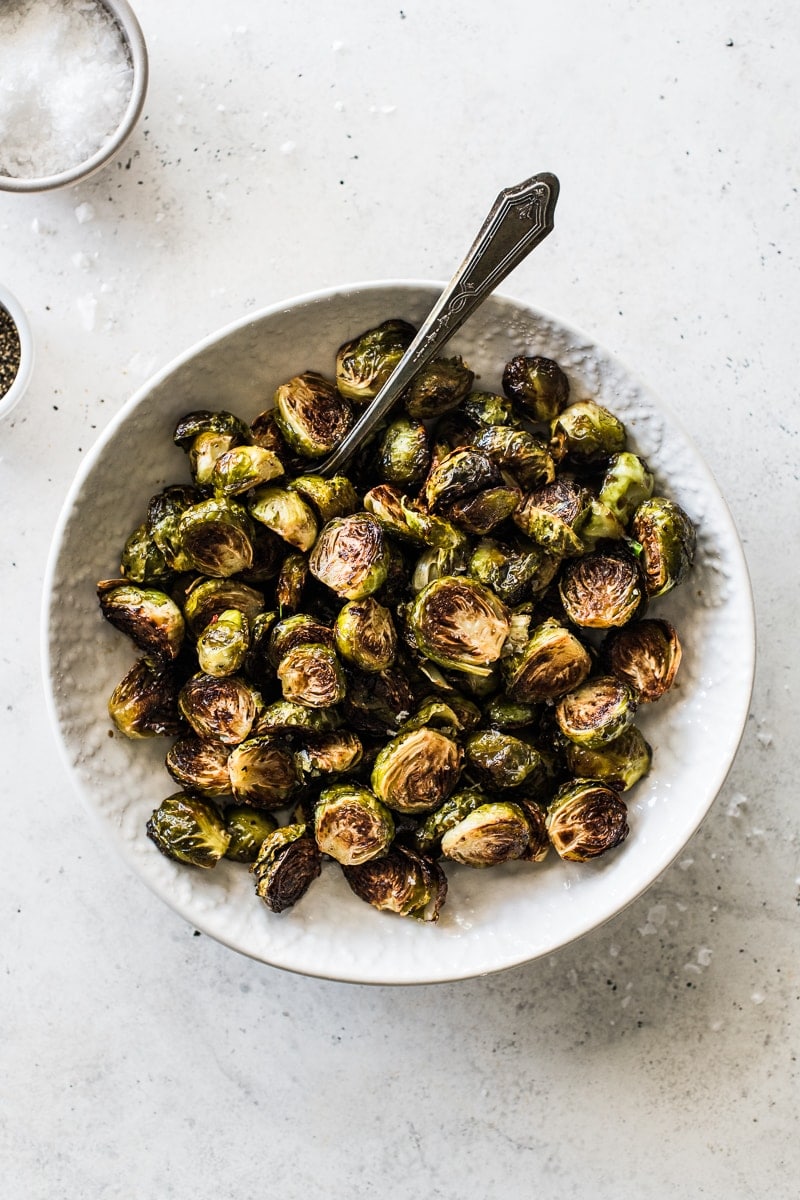 Roasted honey balsamic brussel sprouts in a bowl topped with sea salt.