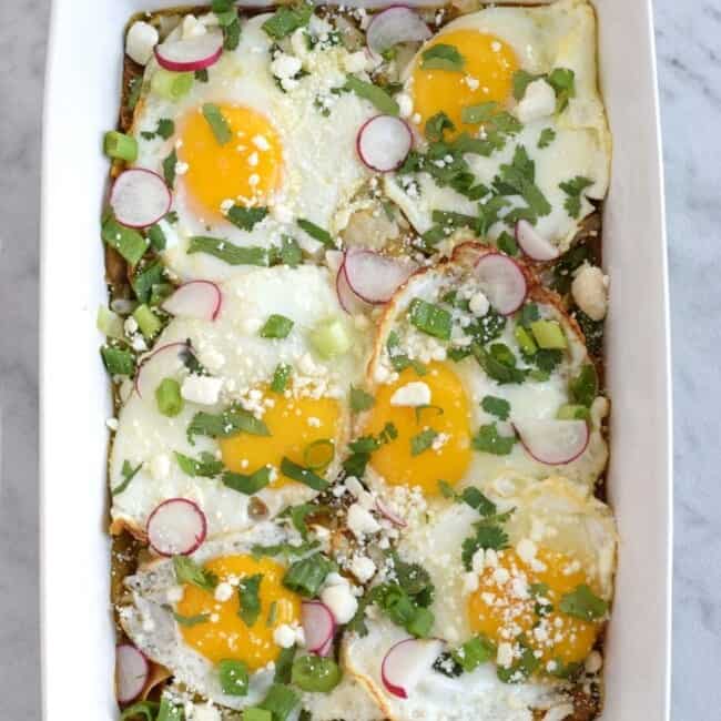 Made with baked corn tortillas covered in salsa verde and topped with sunny side-up eggs, fresh cilantro, radishes and green onions, this Mexican Salsa Verde Chilaquiles Casserole is the perfect breakfast and brunch dish. It's also gluten free and vegetarian, woo woo!