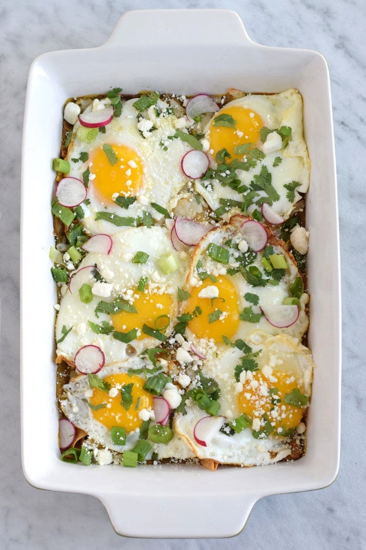 Made with baked corn tortillas covered in salsa verde and topped with sunny side-up eggs, fresh cilantro, radishes and green onions, this Mexican Salsa Verde Chilaquiles Casserole is the perfect breakfast and brunch dish. It's also gluten free and vegetarian, woo woo!