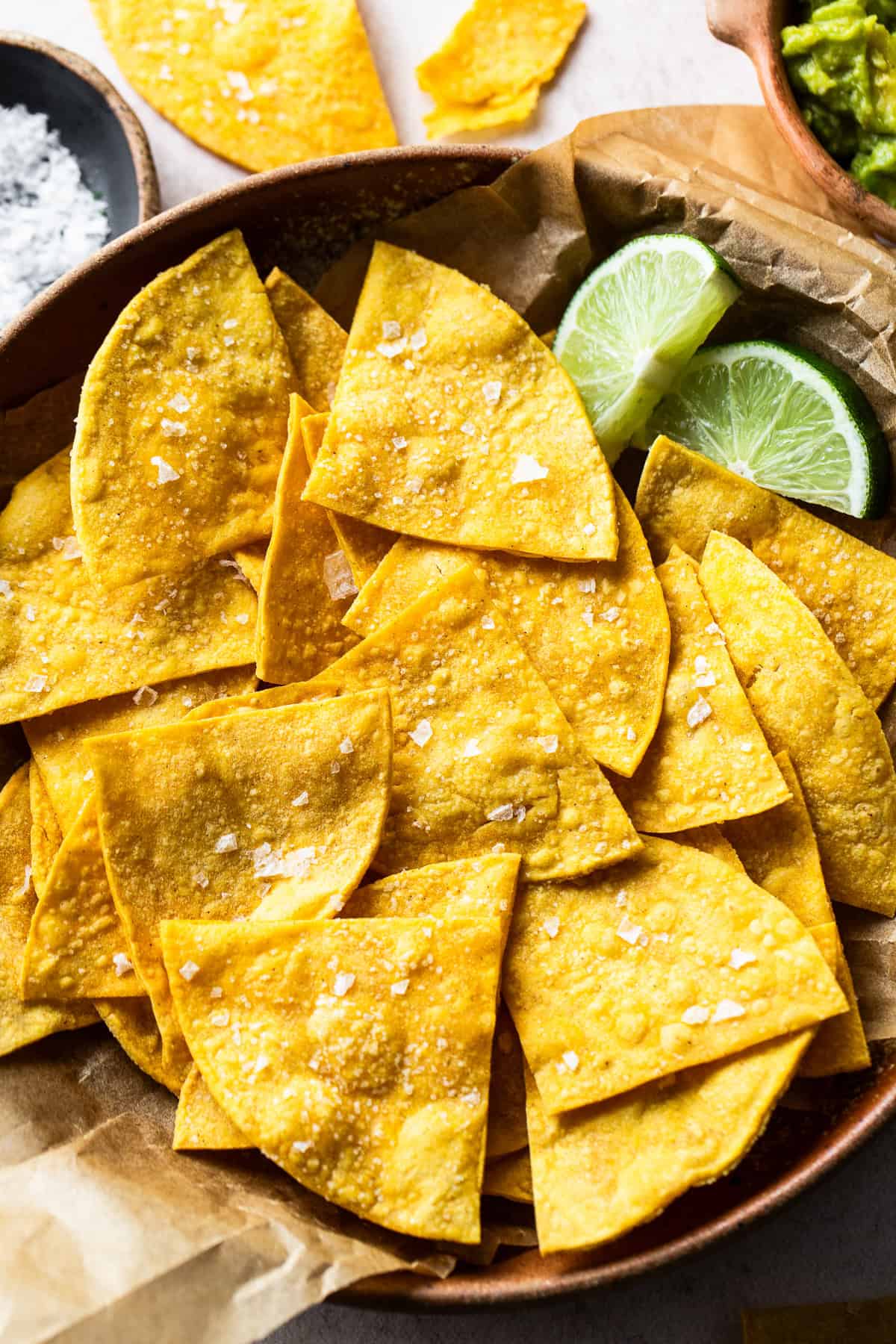 Baked tortilla chips in a bowl garnished with sea salt.
