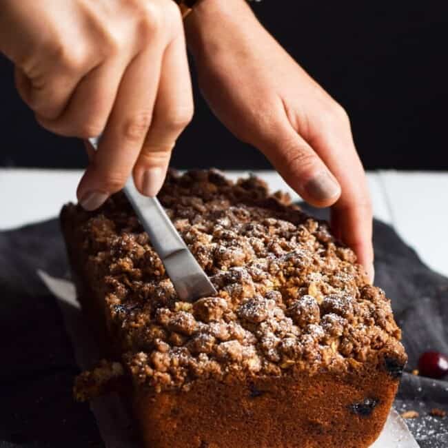 This Cinnamon Cranberry Crunch Banana Bread is super moist, fluffy, filled with cranberries and topped with a granola crumble. Perfect for the holidays!