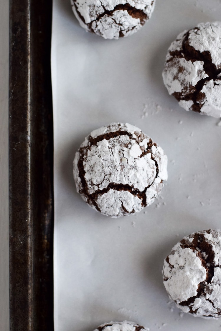 One chocolate crinkle cookie on a baking sheet.