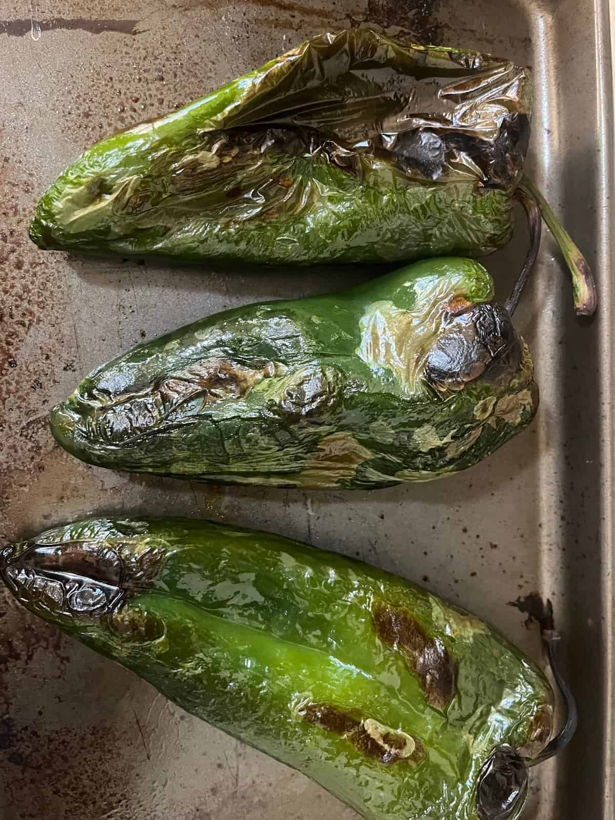 Roasted poblano peppers on a baking sheet.