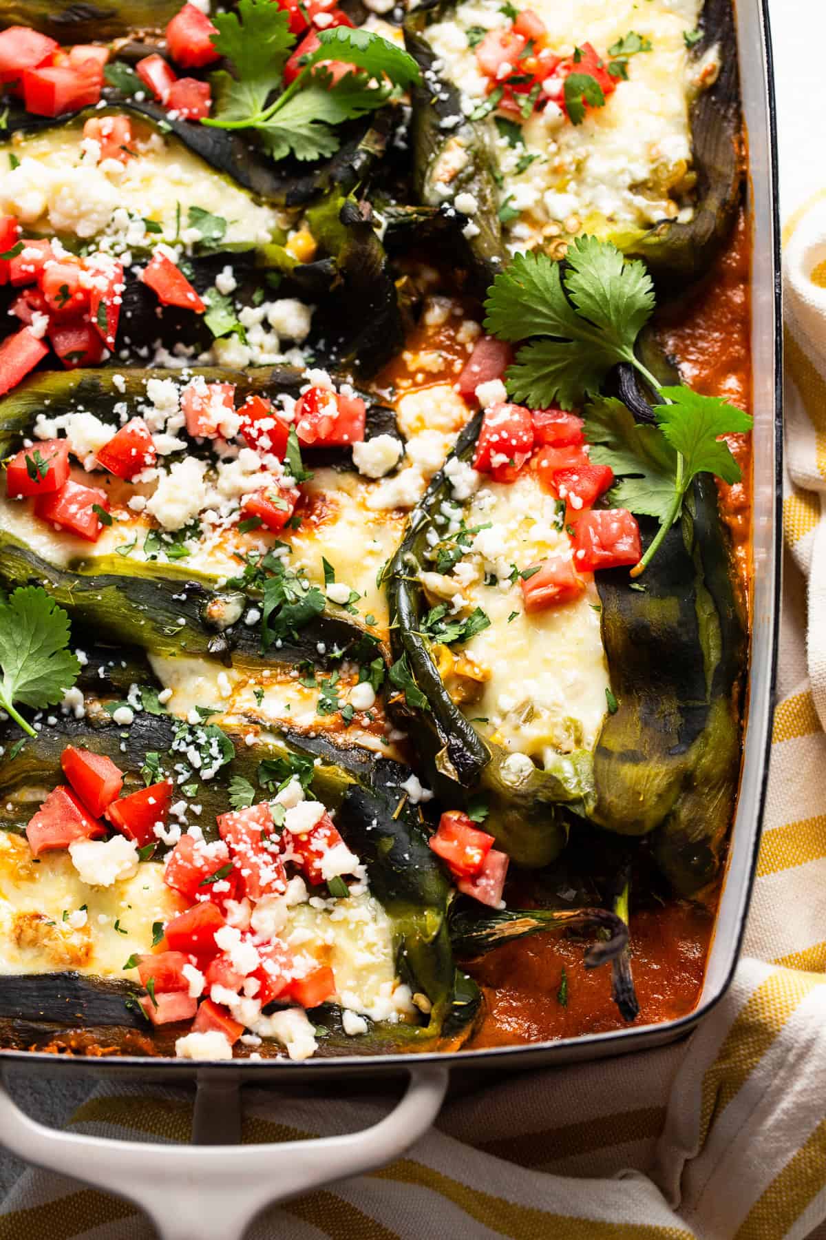 Baked chile relleno topped with diced tomatoes, cilantro, and cotija cheese.