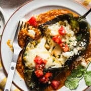 Baked chile relleno on a plate with ranchero sauce.