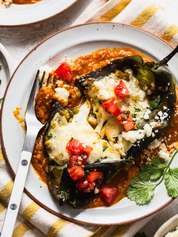 Baked chile relleno on a plate with ranchero sauce.