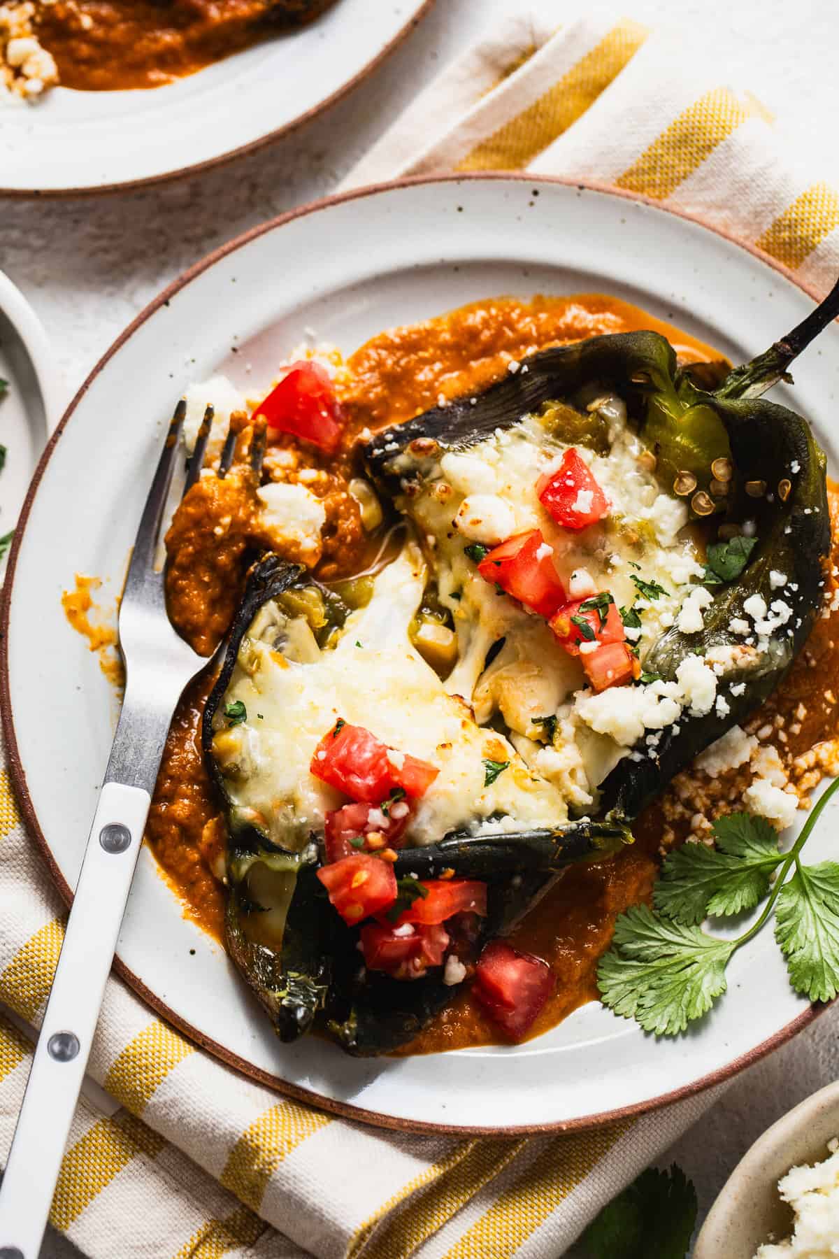 Baked chile relleno on a plate with ranchero sauce.