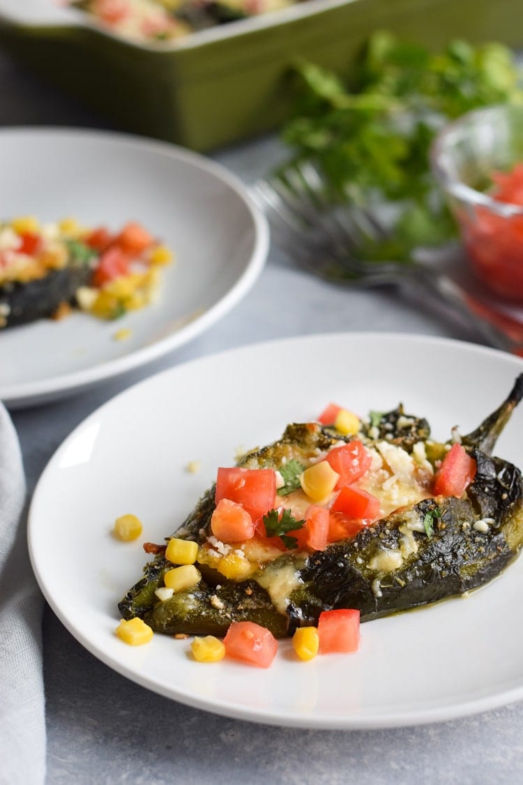 Baked chile rellenos topped with cilantro and tomatoes.