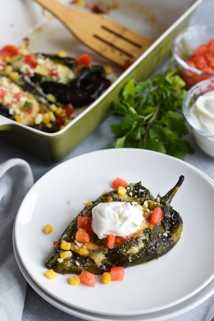 Baked chile relleno on a plate topped with sour cream.