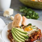 shakshuka on a plate with avocado slices and bread