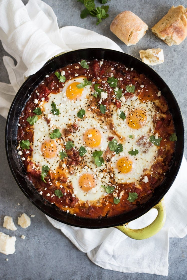 Shakshuka recipe in a cast iron skillet topped with cilantro and cotija cheese.