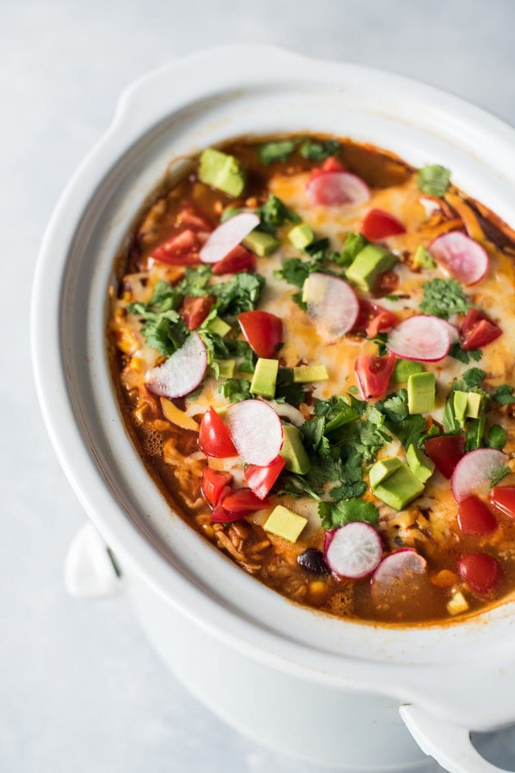 This Slow Cooker Mexican Lasagna is made with layers of black beans, corn tortillas and red enchilada sauce for a delicious gluten free weeknight meal!