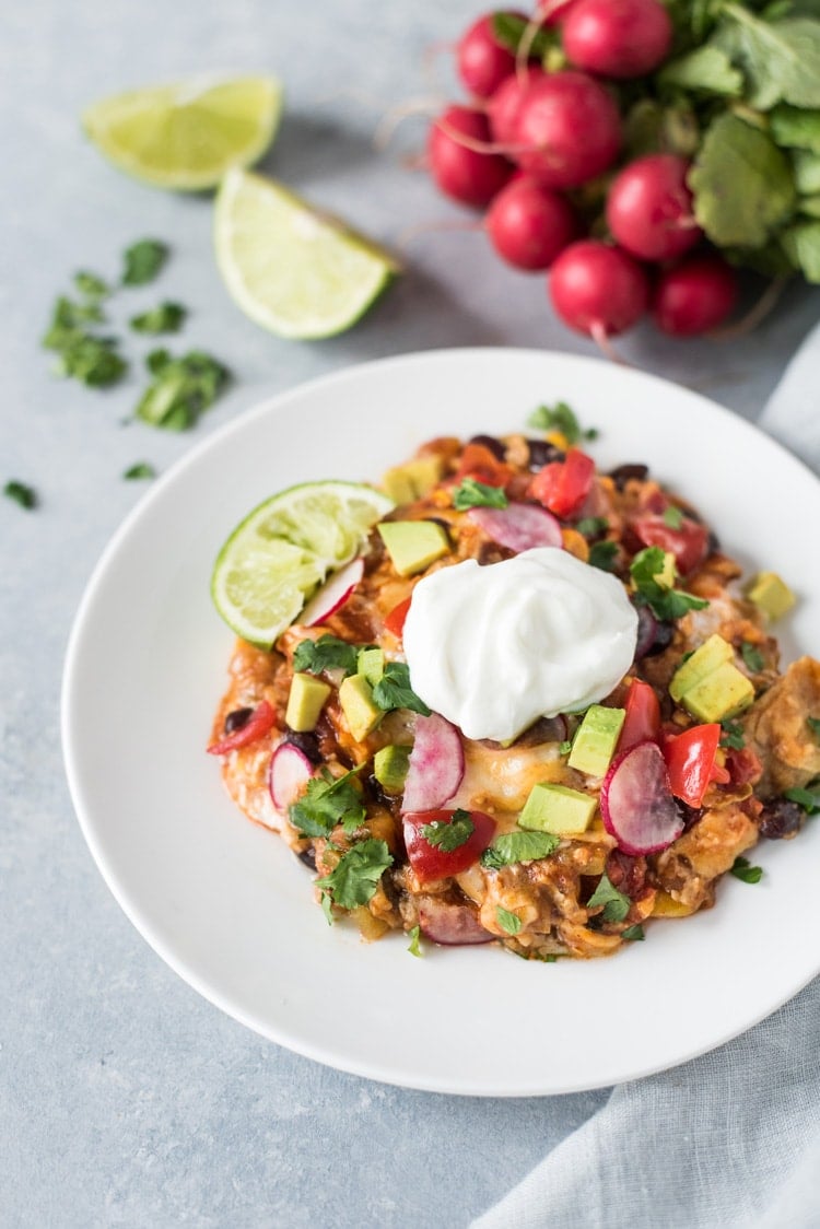 This Slow Cooker Mexican Lasagna is made with layers of black beans, corn tortillas and red enchilada sauce for a delicious gluten free weeknight meal!