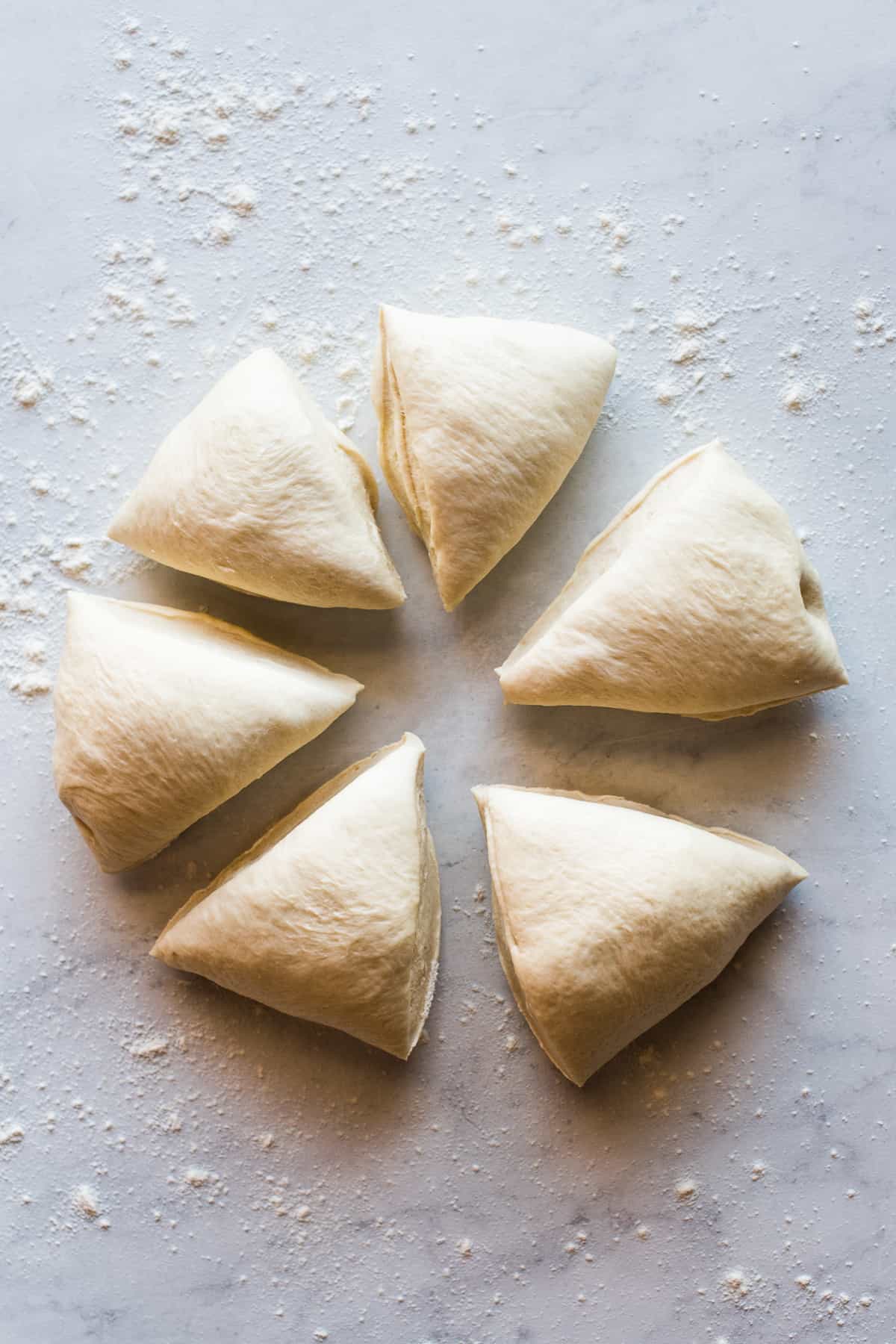 Risen bolillo bread dough divided into 6 pieces.