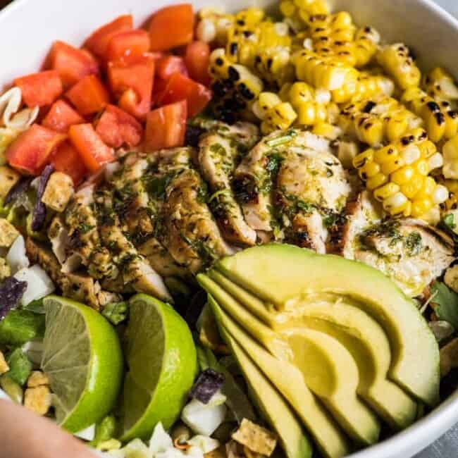 A bright, fresh Mexican Chimichurri Chicken Salad featuring grilled corn, summer tomatoes, marinated and grilled chimichurri chicken and creamy avocados. (gluten free)