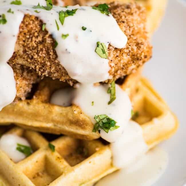 These savory Jalapeno Cornbread waffles are topped with crispy oven baked chicken tenders and white gravy for the ultimate brunch dish!