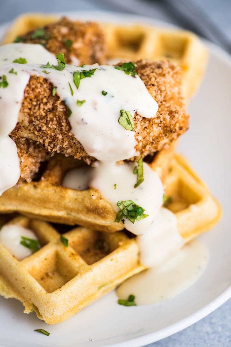 These savory Jalapeno Cornbread waffles are topped with crispy oven baked chicken tenders and white gravy for the ultimate brunch dish!