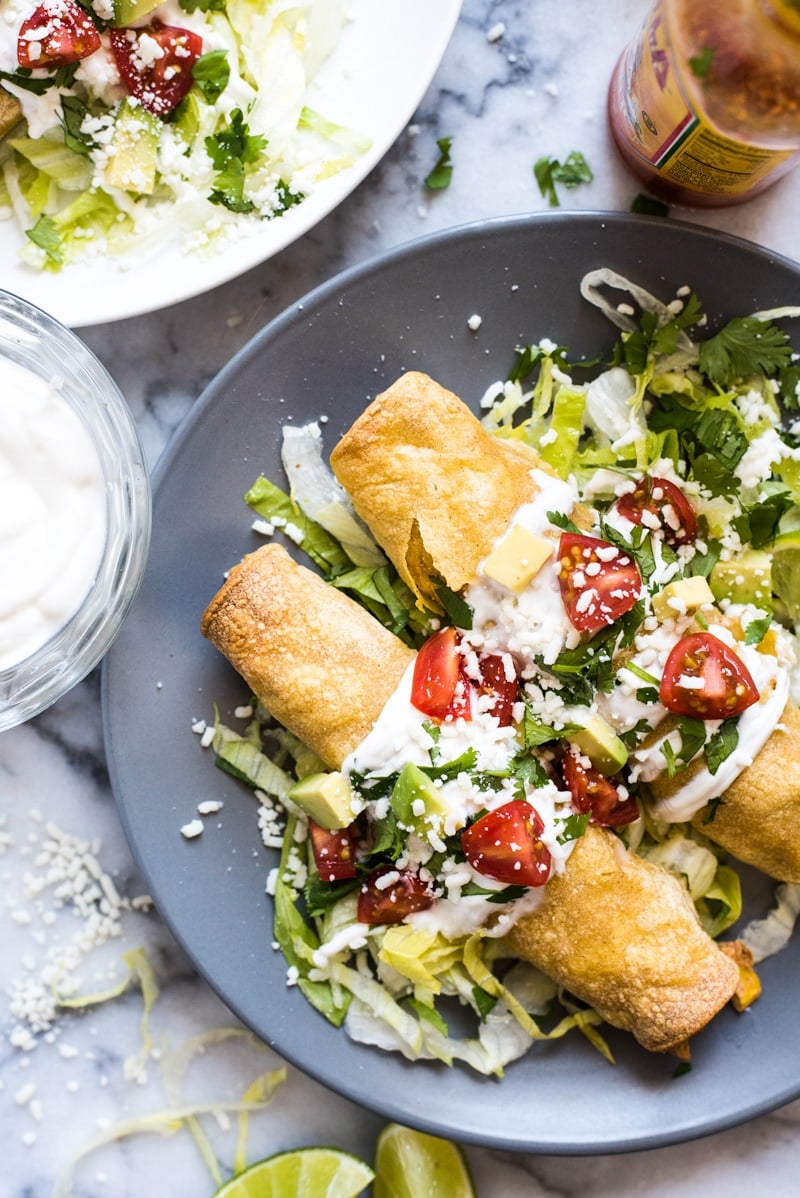 These baked Chicken Taquitos are stuffed with seasoned shredded chicken, cream cheese, diced green chiles, black beans and corn. Perfect for any weeknight meal! (freezer friendly, gluten free)