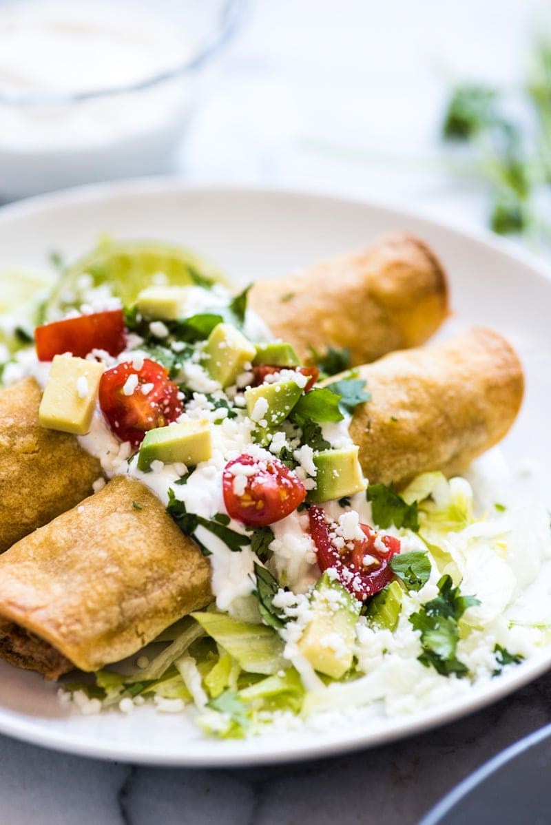 These baked Chicken Taquitos are stuffed with seasoned shredded chicken, cream cheese, diced green chiles, black beans and corn. Perfect for any weeknight meal! (freezer friendly, gluten free)