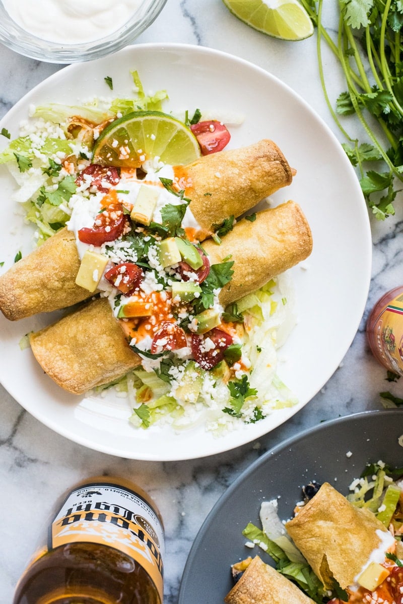 These baked Chicken Taquitos are stuffed with seasoned shredded chicken, cream cheese, diced green chiles, black beans and corn. Perfect for any weeknight meal!