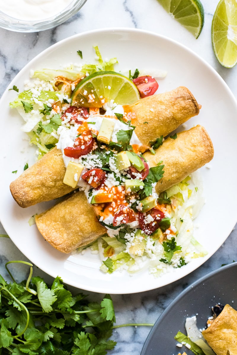 These baked Chicken Taquitos are stuffed with seasoned shredded chicken, cream cheese, diced green chiles, black beans and corn. Perfect for any weeknight meal! (freezer friendly, gluten free)