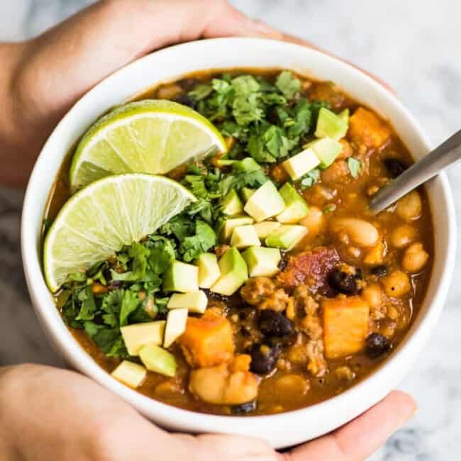Turkey Pumpkin Chili in a white bowl topped with avocado and cilantro.