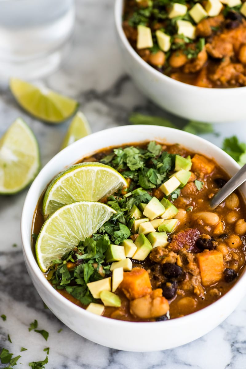 Turkey chili in two white bowls on a marble table.