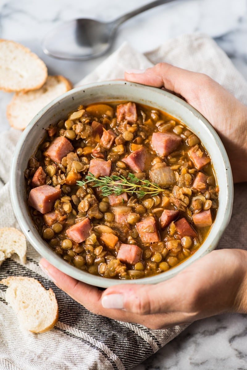 Hands holding a bowl of lentil soup.
