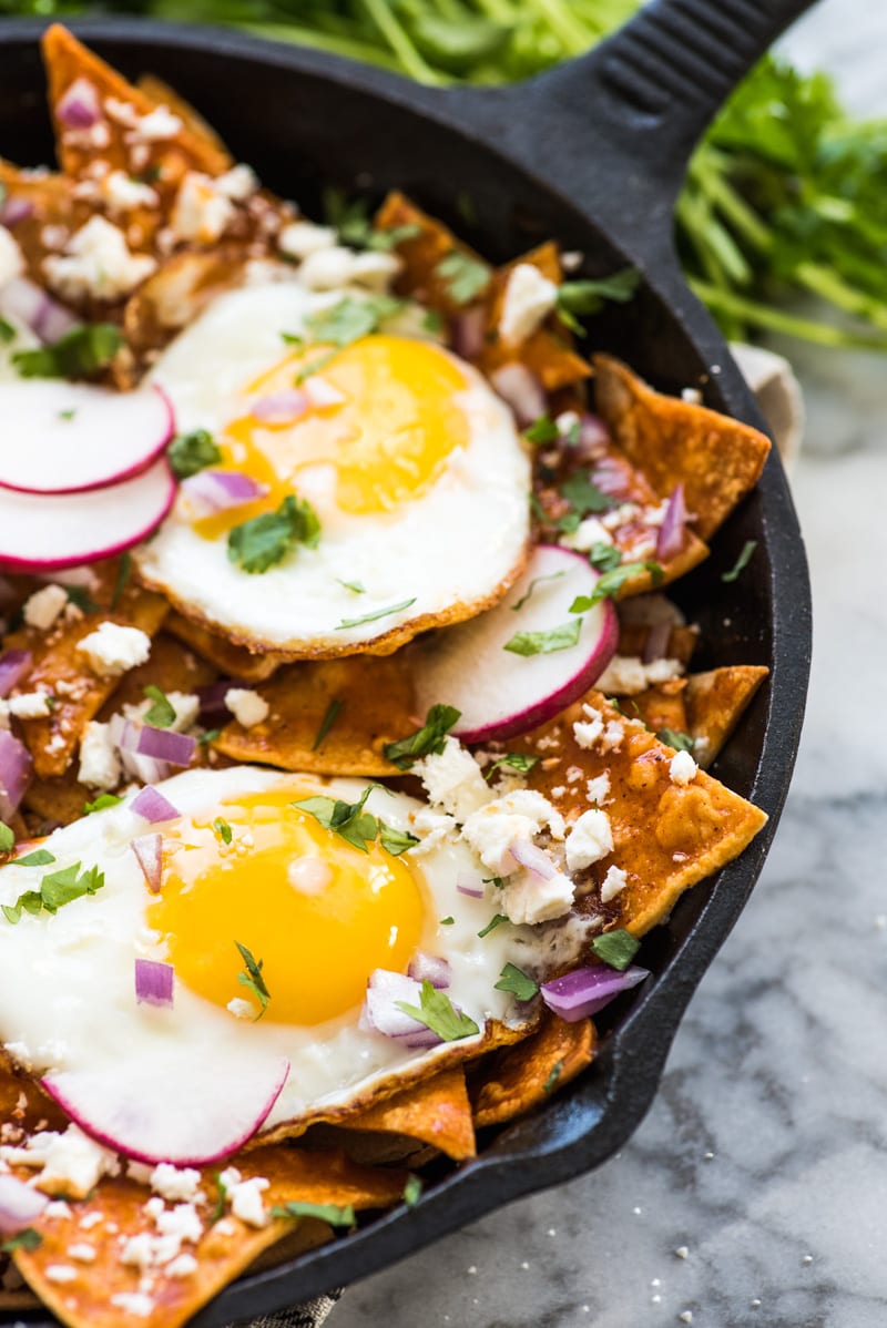 Red chilaquiles made from corn tortillas and enchilada sauce in a cast iron skillet.
