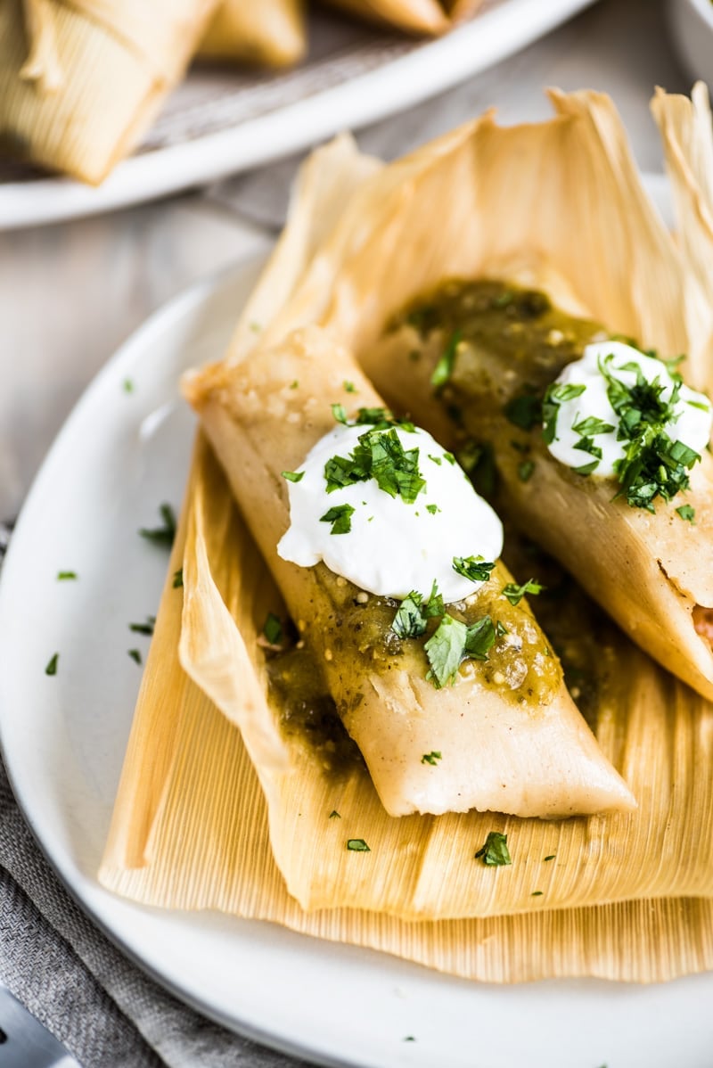 Tamales de Rajas ready to eat topped with salsa verde, sour cream, and cilantro.