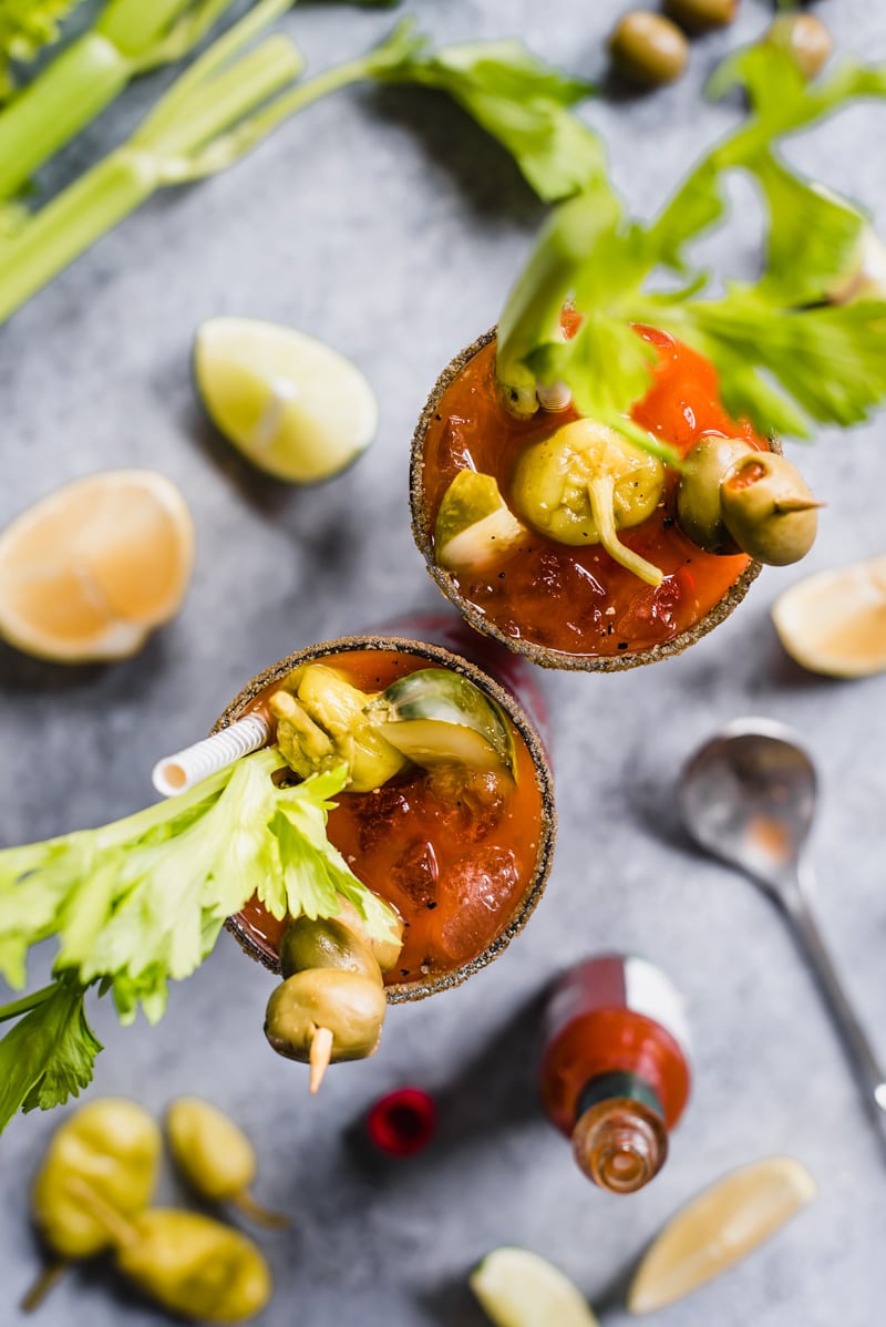 Overhead view of two Bloody Maria cocktails on a grey counter.