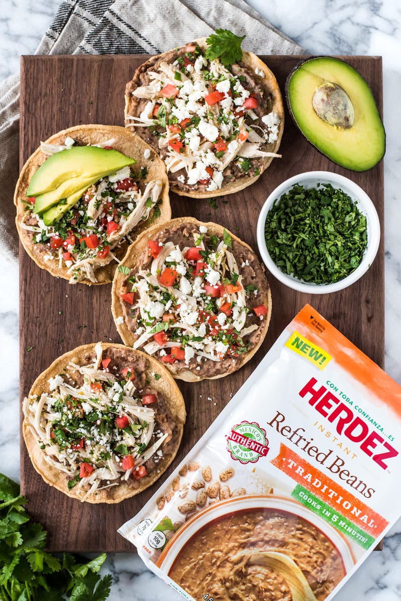 These crispy and crunchy Slow Cooker Salsa Verde Chicken Tostadas are topped with a layer of delicious refried beans, salsa verde chicken, tomatoes, cilantro, queso fresco and avocados.