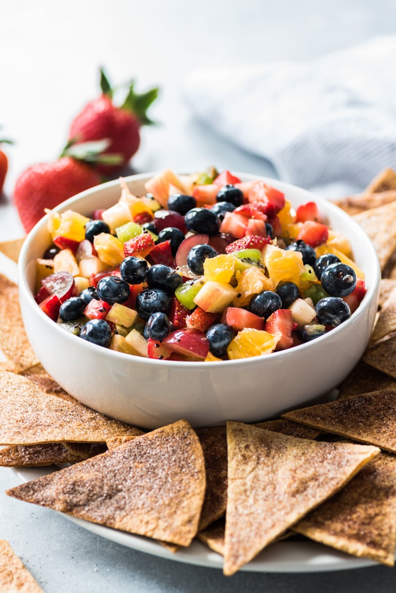 This Fruit Salsa Recipe with Cinnamon Chips is made with 6 different types of fruit and is served with baked cinnamon sugar tortilla chips for a fun appetizer or healthy dessert!