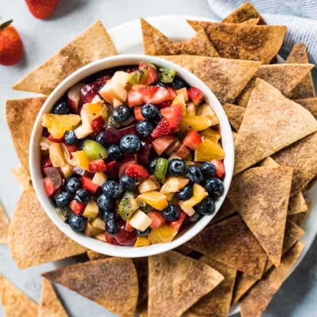 This Fruit Salsa with Cinnamon Chips recipe is made with 6 different types of fruit and is served with baked cinnamon sugar tortilla chips for a fun appetizer or healthy dessert!