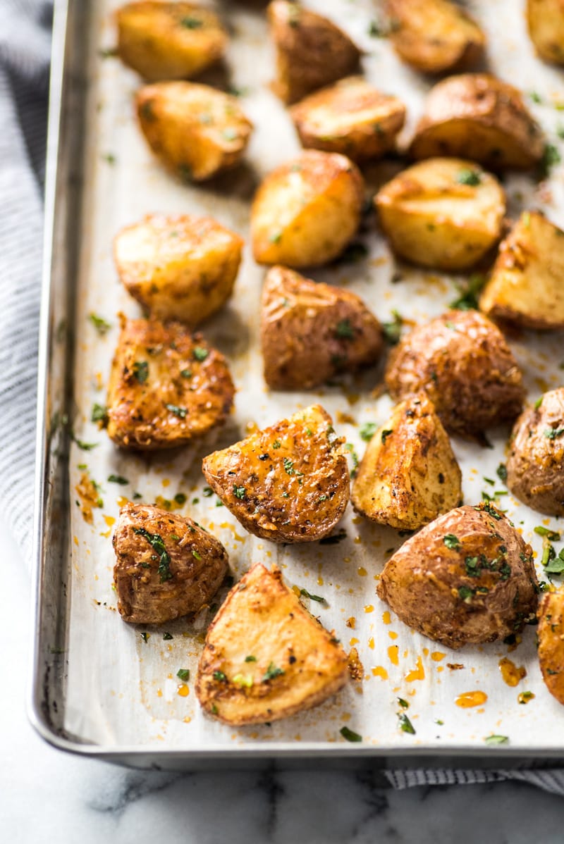 Mexican potatoes on a baking sheet topped with cilantro and cheese.