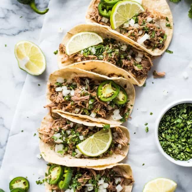 Juicy pork carnitas in warm corn tortillas topped with cilantro, onions and limes.