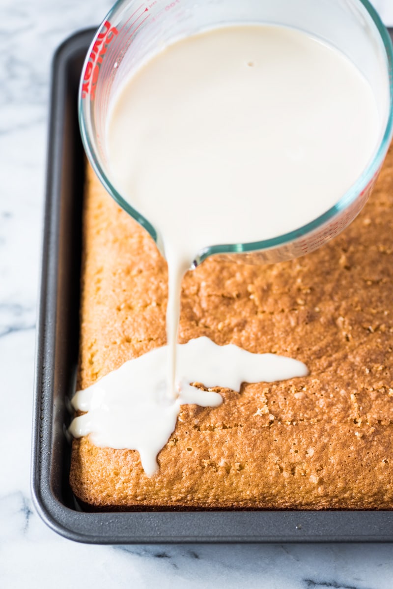 Pouring three milk mixture over tres leches cake.