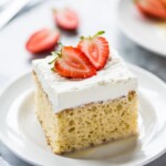 A slice of tres leches cake topped with fresh strawberries