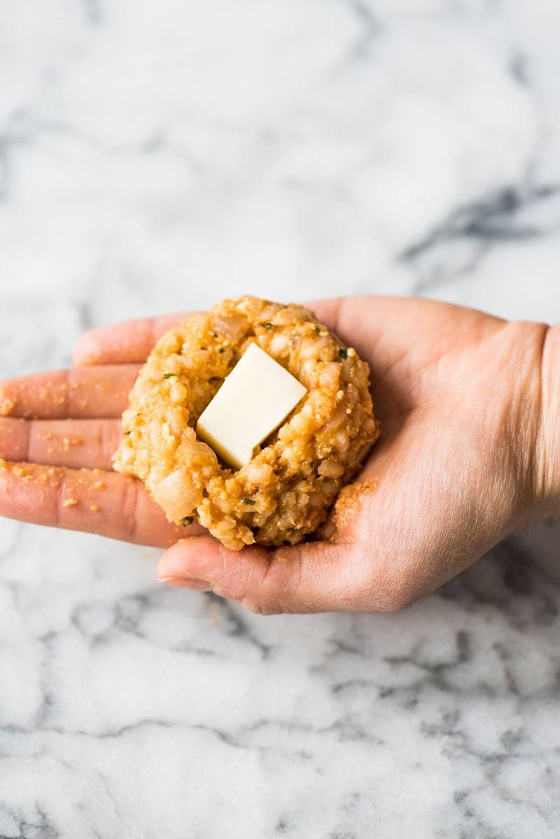 Adding cheese to the arancini rice ball.