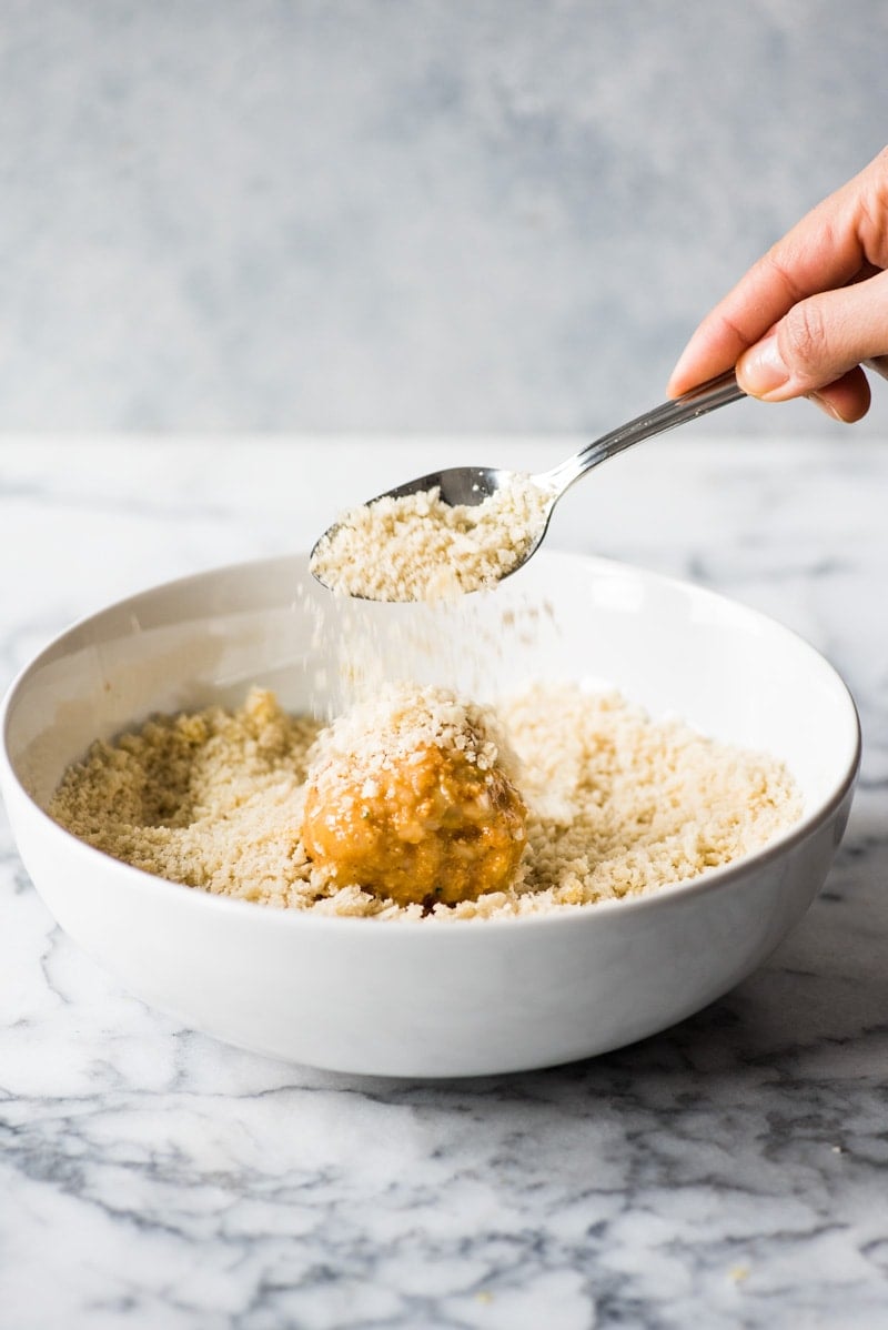 Covering arancini in panko breadcrumbs.