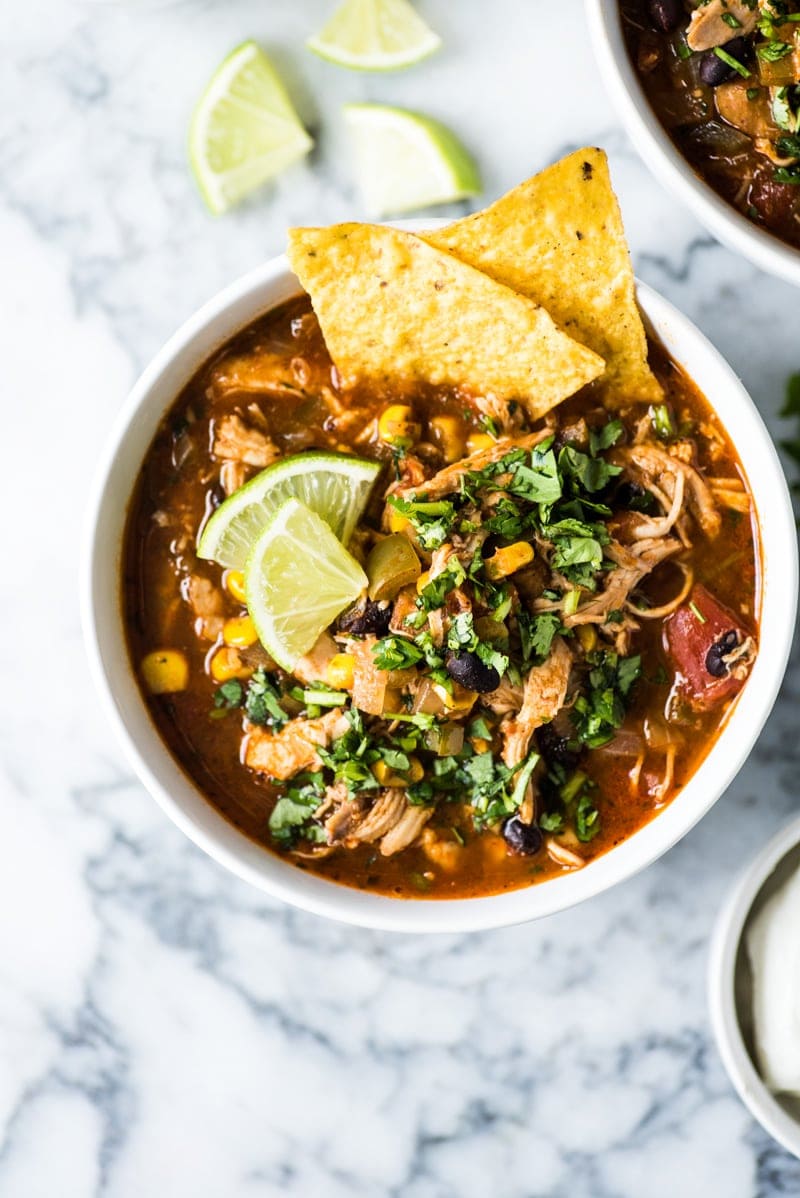 A bowl of chicken tortilla soup topped with cilantro and tortilla chips.