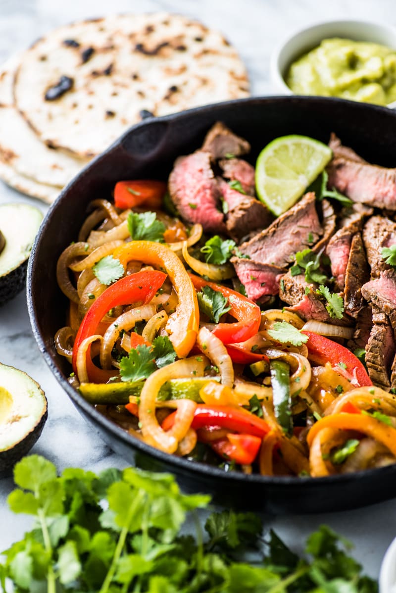 Peppers and onions in a black cast iron skillet with steak fajitas.