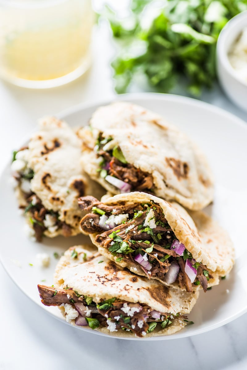 Gorditas filled with shredded beef on a white plate.