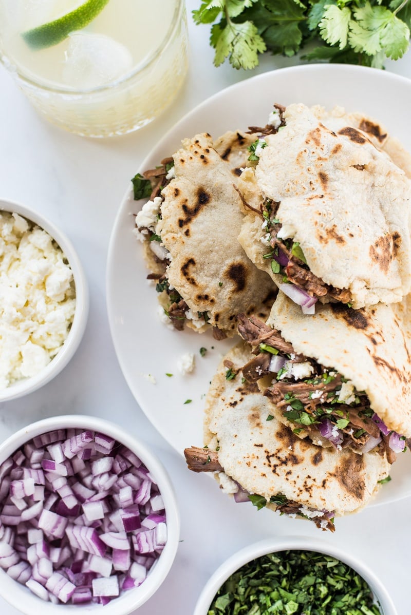 Gorditas on a white plate stuffed with shredded meat and cheese