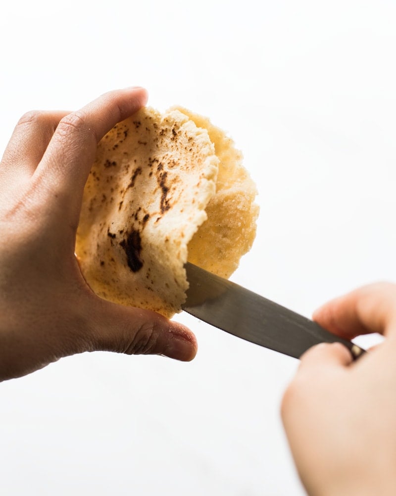 Cutting open a gordita with a knife to reveal a little pocket inside