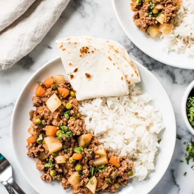top down shot of picadillo on a plate with rice and a tortilla